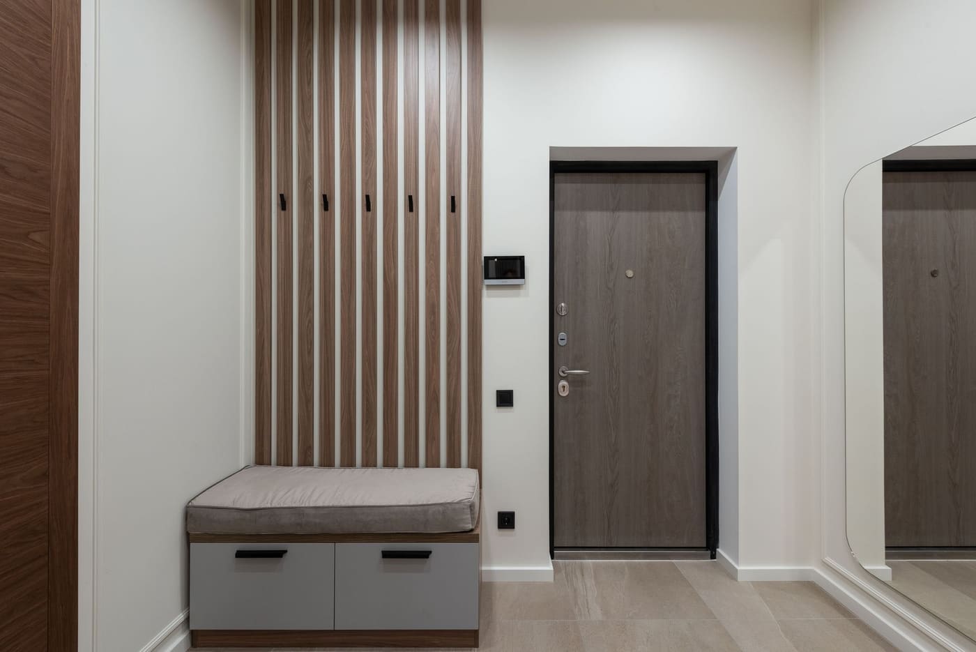 Tidy entryway with a slatted wall of hooks, a storage bench with drawers and a front door