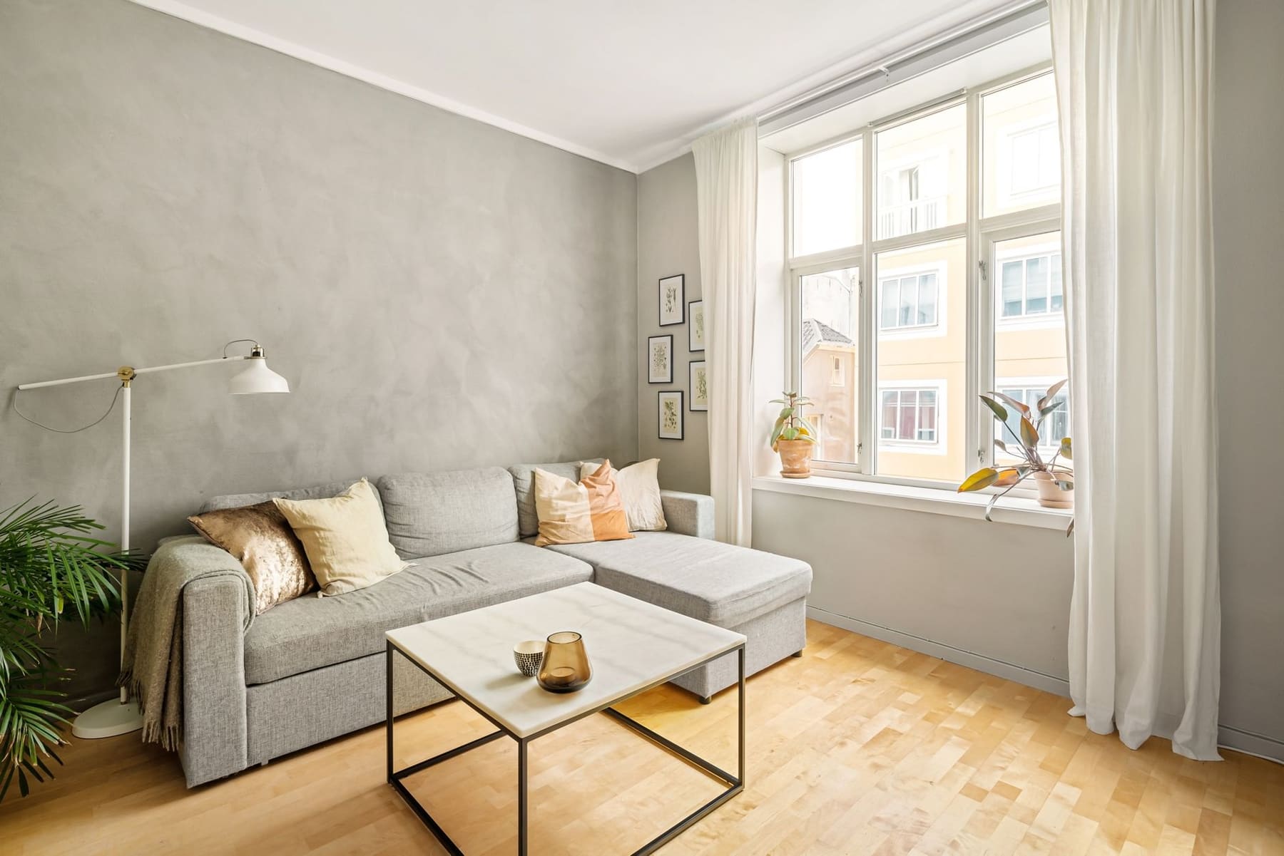 A bright living room with a gray sofa and a large window