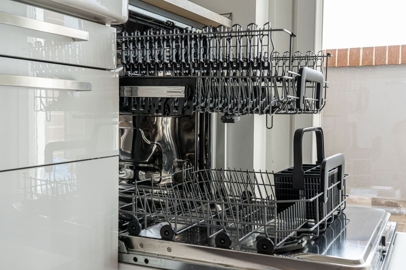 Open empty dishwasher in a sunlit kitchen with clear counters